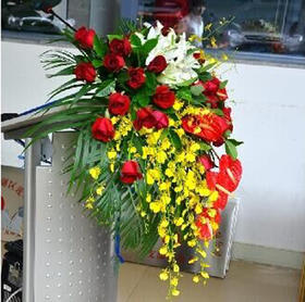 讲台花4   20支红玫瑰，10支跳舞兰，5朵白百合，5支红掌，其他绿色叶材及散尾葵适量 长度约60-70cm(1406)
